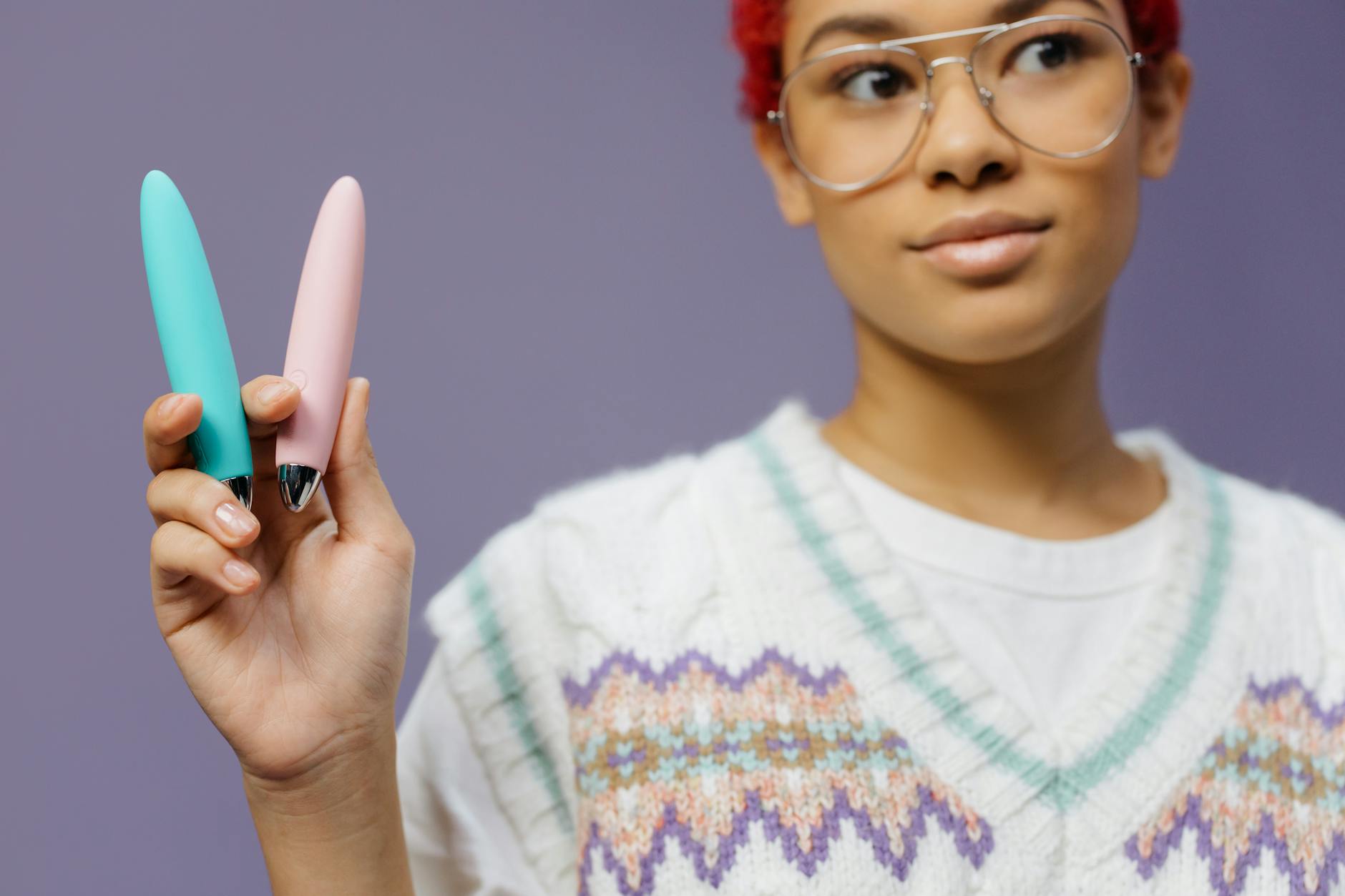 A person holds two colorful vibrators, exploring pleasure with modern tools