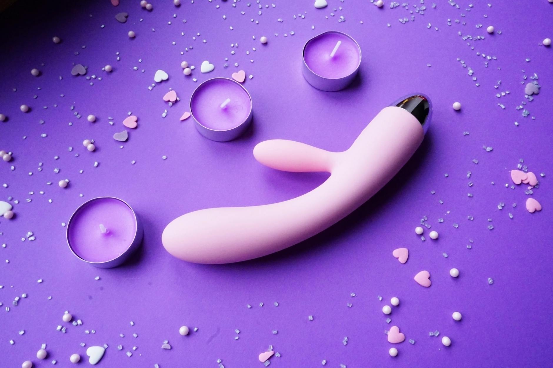 Silicone clitoral vibrator on a bright yellow background surrounded by fresh fruit